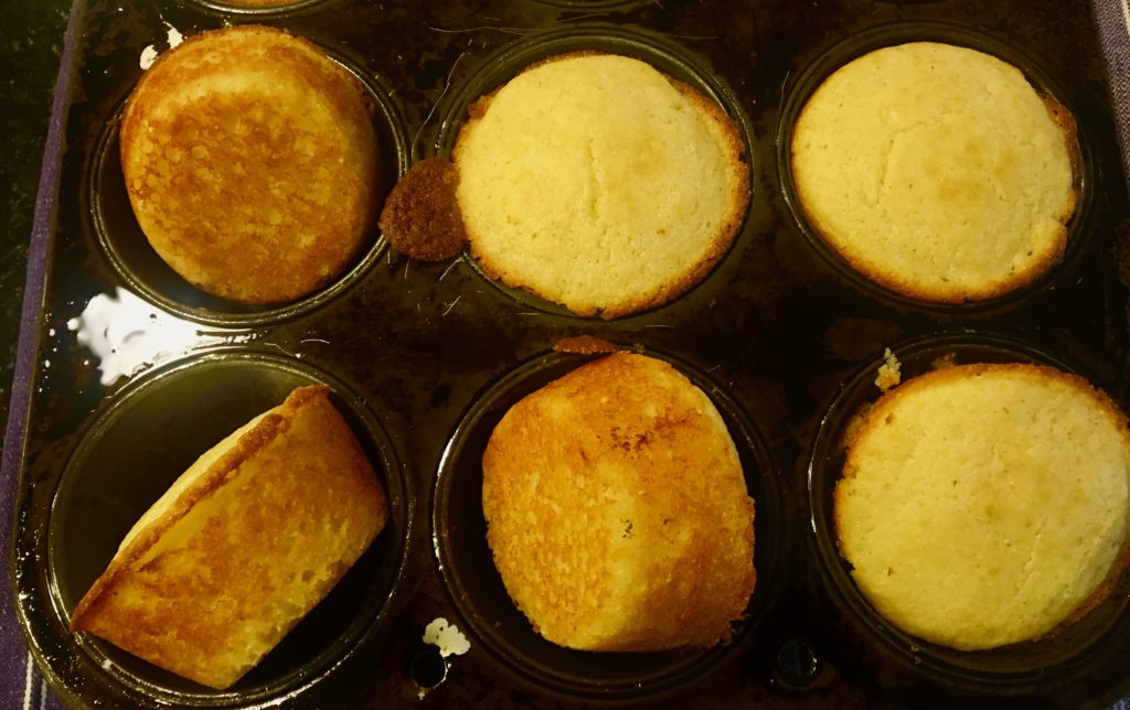 A blackened six muffin pan filled with golden brown cornbread muffins