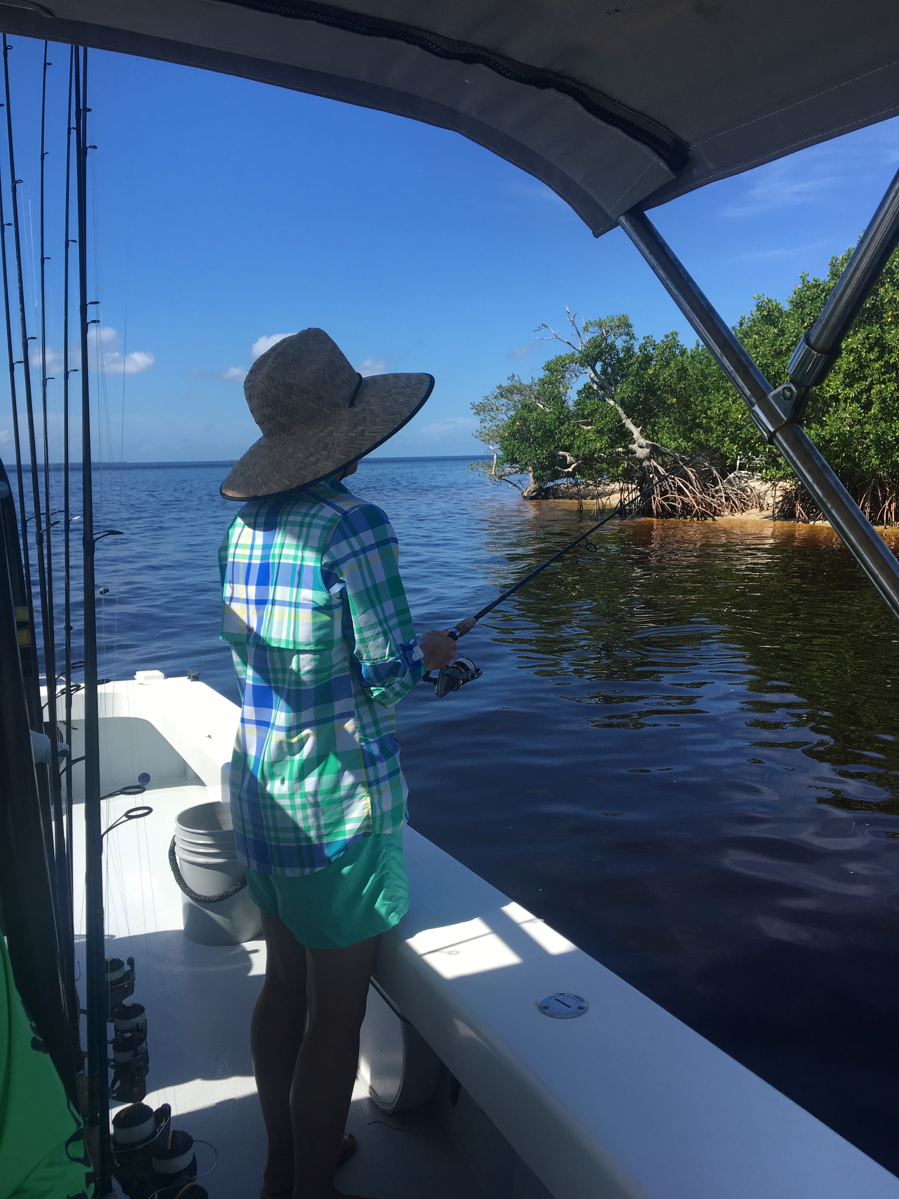 A woman fishing in a small boat in a lagoon 