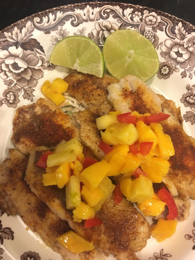 A plate with snapper filets topped with mango salsa 