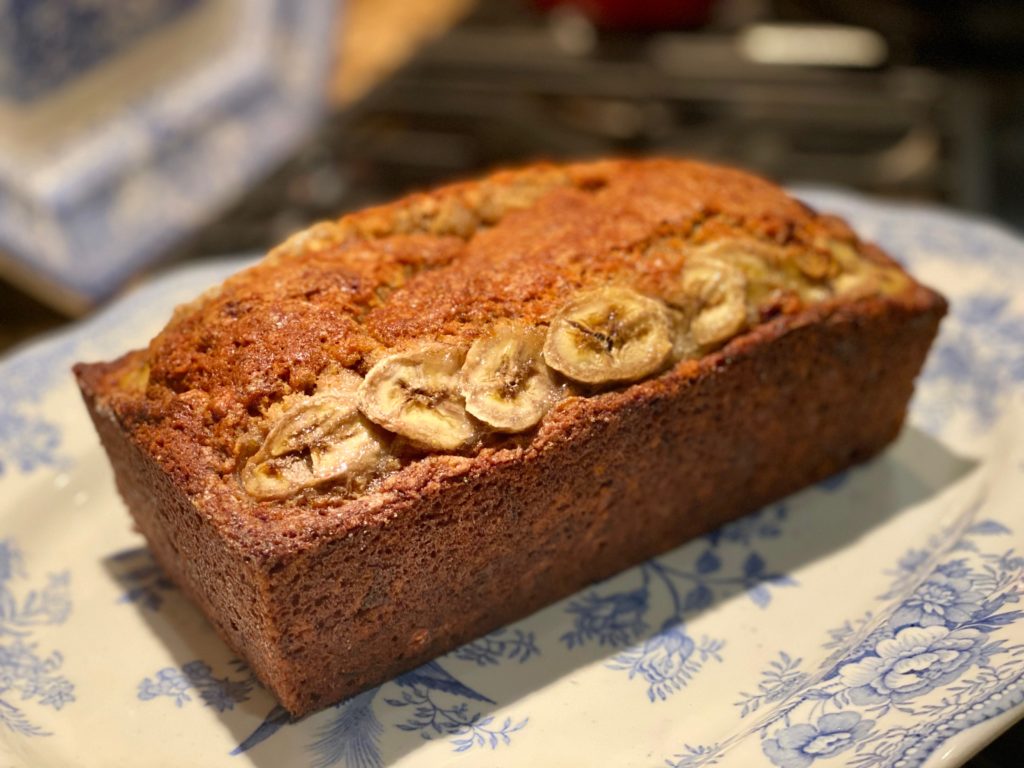 A loaf of warm banana bread on a blue and white platter 