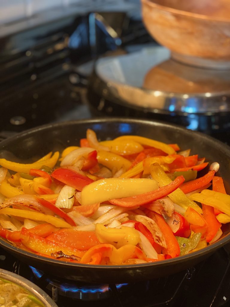 a large black skillet filled with peppers and onions 