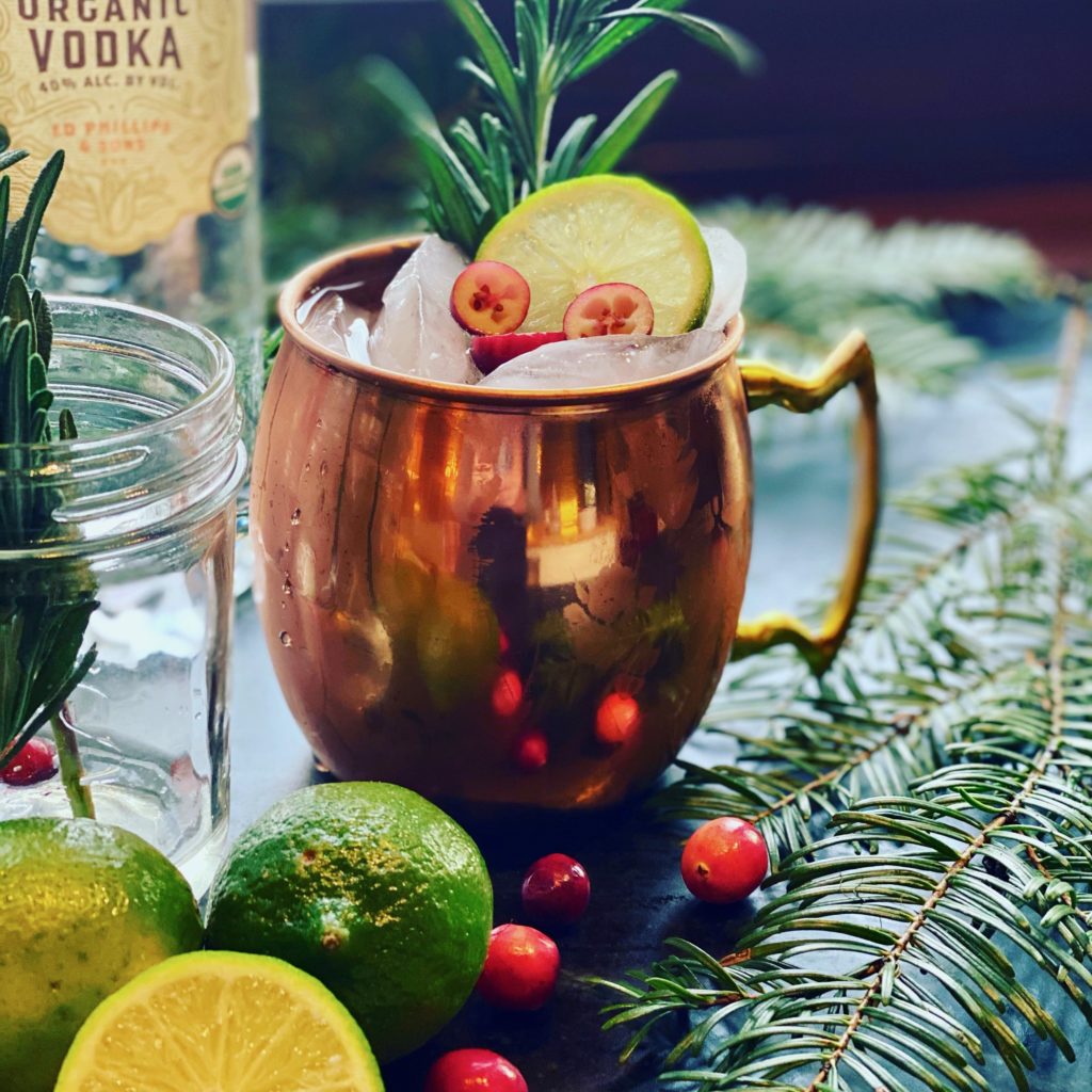 a copper mug filled with rosemary lime slices and sliced cranberries 
