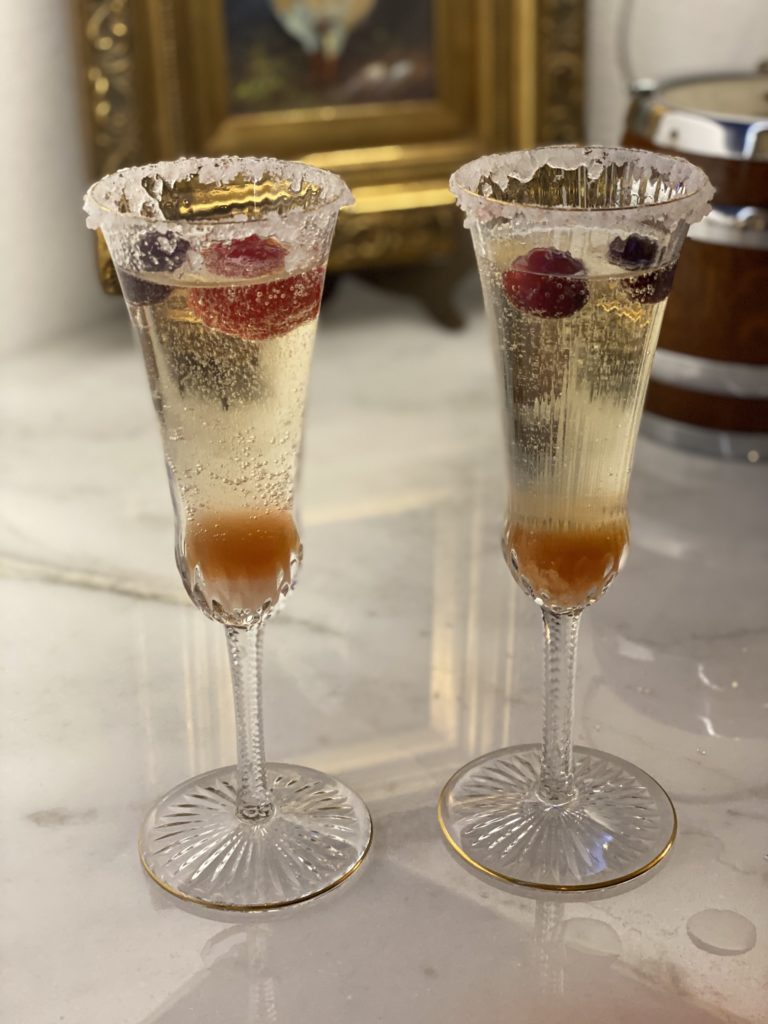two champagne flutes filled with fruit and champagne
