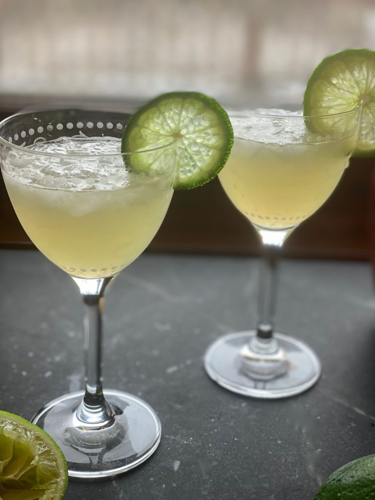 two lime daiquiris garnished with a thin slice of lime