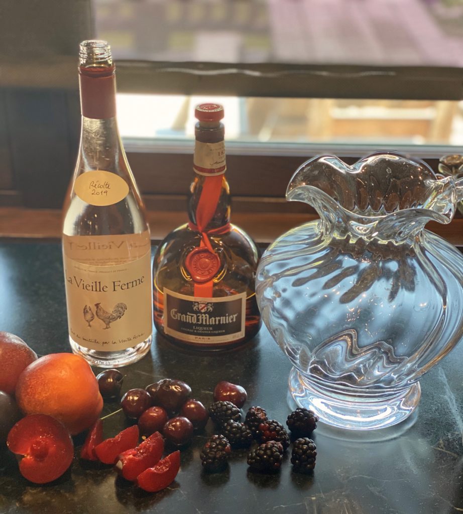 a glass pitcher next to peaches and cherries