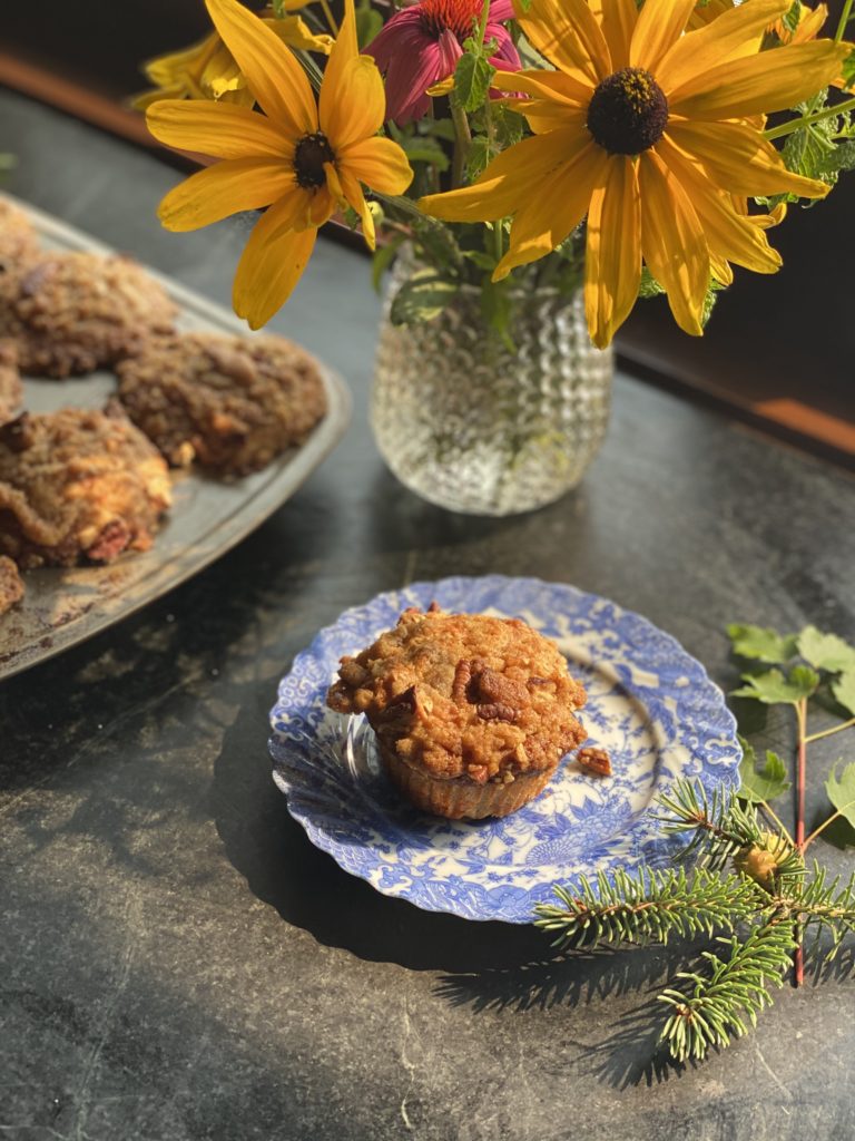 a muffins on a blue antique plate next to a vase of black eyed Susans