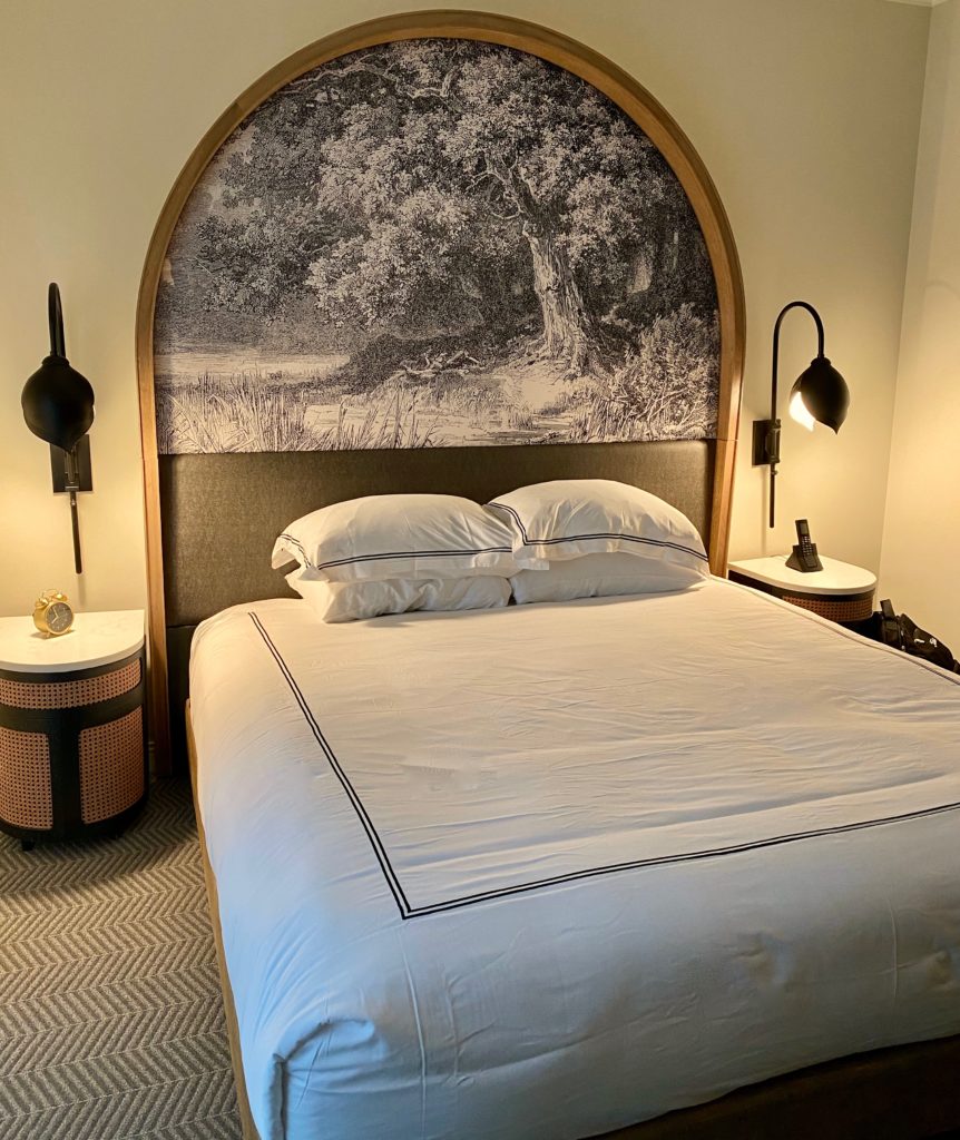 a luxurious hotel bed with a massive mural painted headboard and two bed side lamps- the Kimpton cottonwood