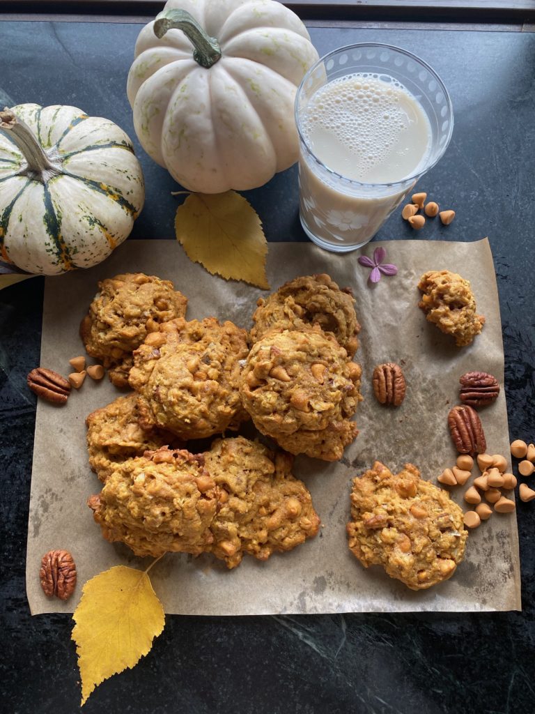 A pile of oatmeal cookies with a glass of milk and autumn leaves 