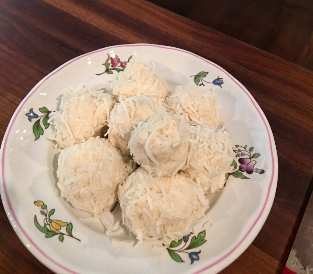 coconut covered balls of lemon on a white plate with flowers 