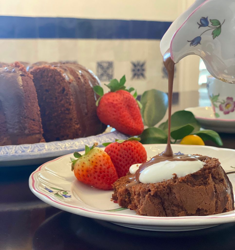 a chocolate bundt cake with a slice of cake next to it and a chocolate glaze being poured over the slice