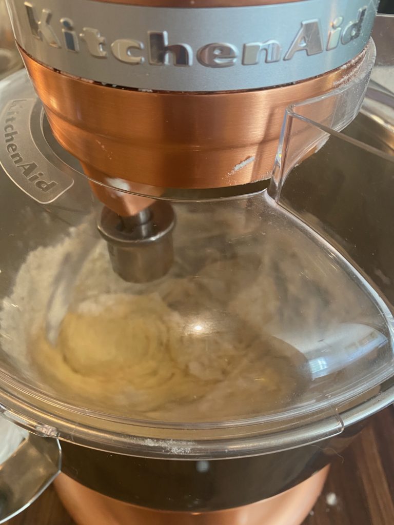 a stand mixer with dough inside of it 