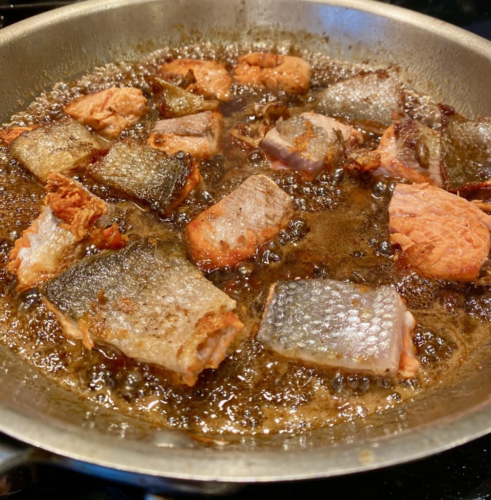 a pan filled with chunks of salmon browning in butter 