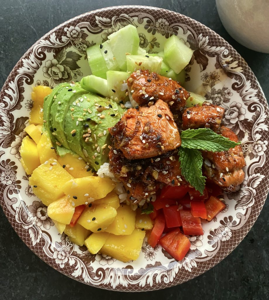 a brown bowl filled with salmon, mango and peppers