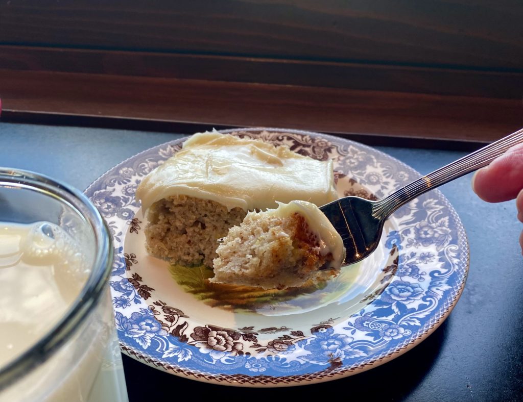 a frosty glass of milk and a bite of cake on a fork 