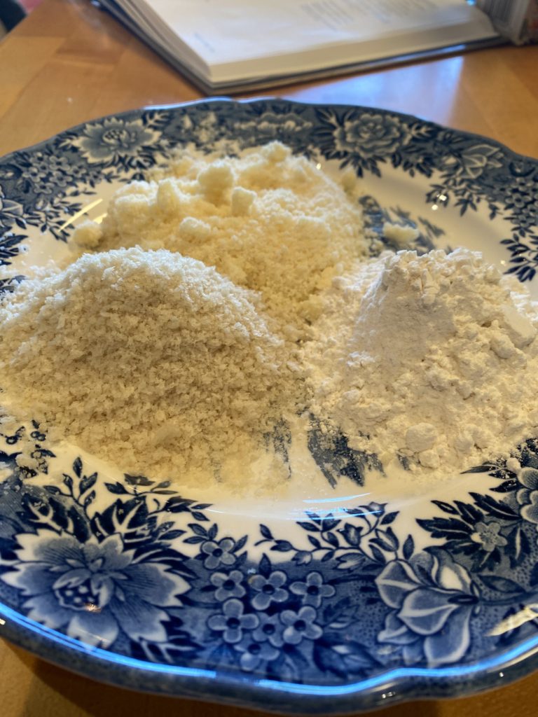 a blue plate with flour , parmesan cheese and bread crumbs

