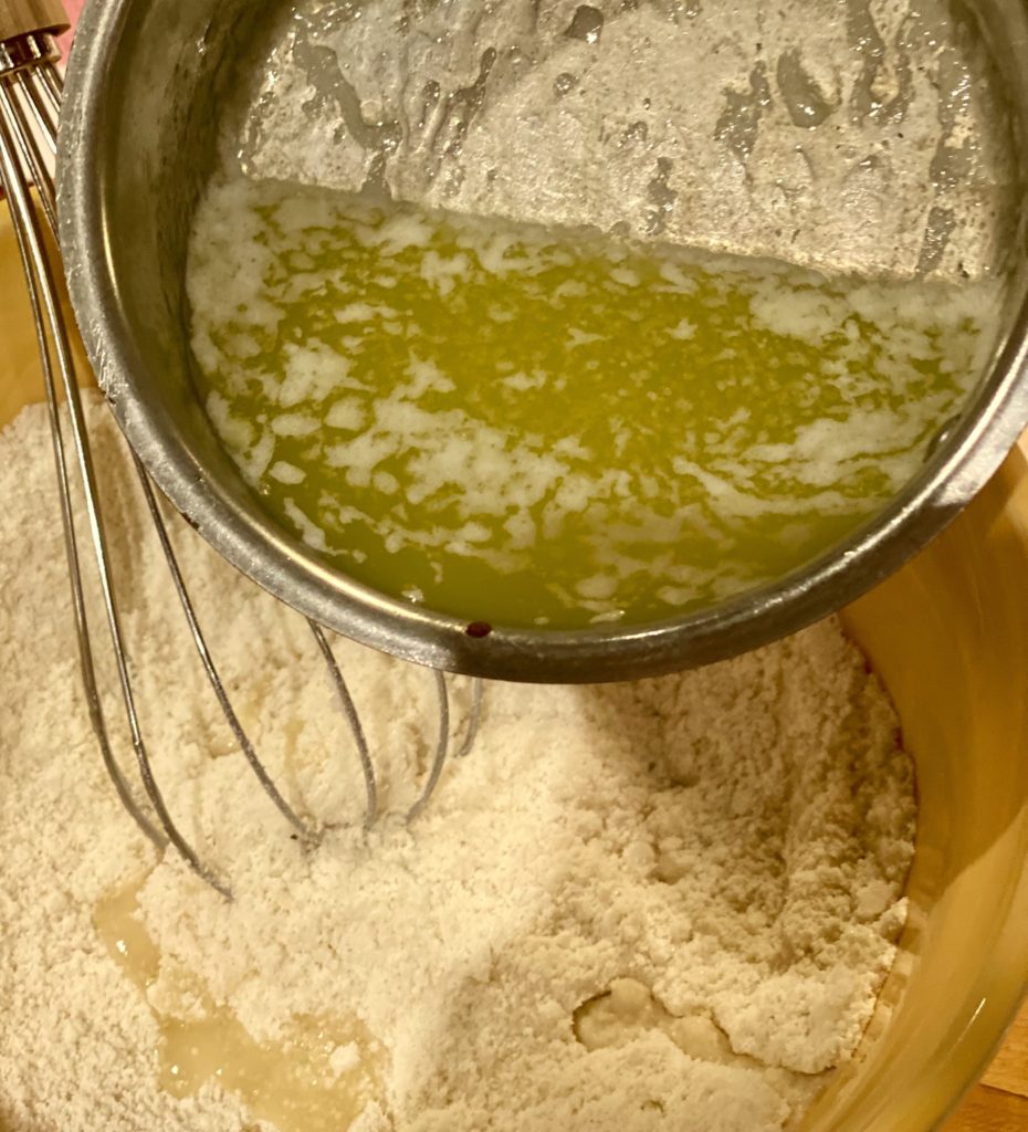 melted butter being poured into a bowl of flour 
