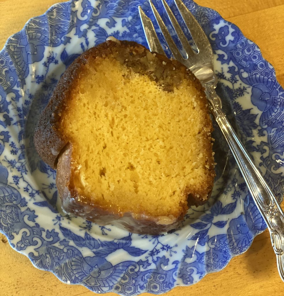 a slice of yellow bundt cake on a blue plate with a sterling silver fork 