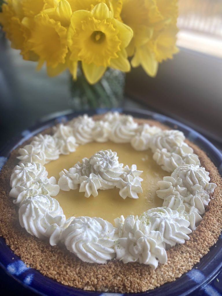 a lime pie with whipped cream and daffodils
