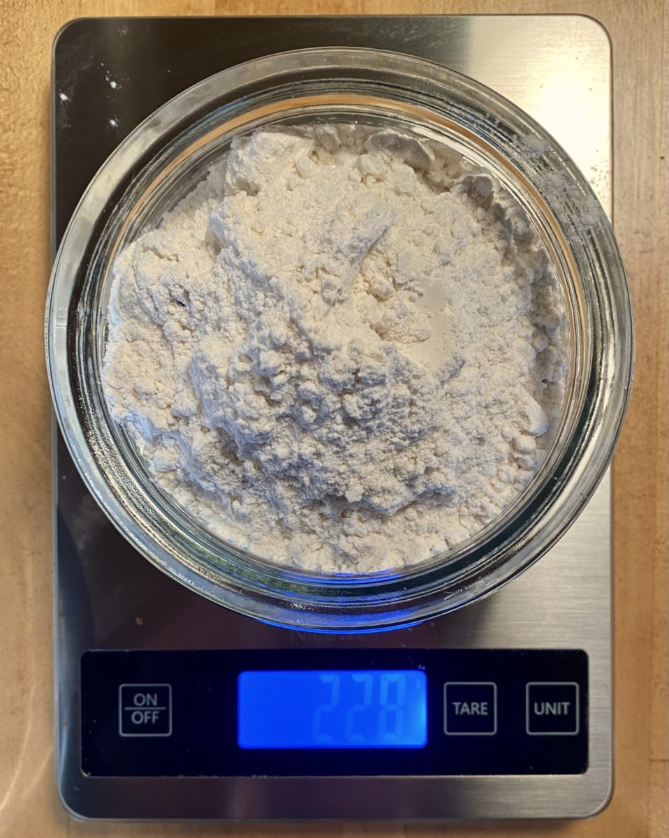 228 grams of flour in a glass bowl on a kitchen scale