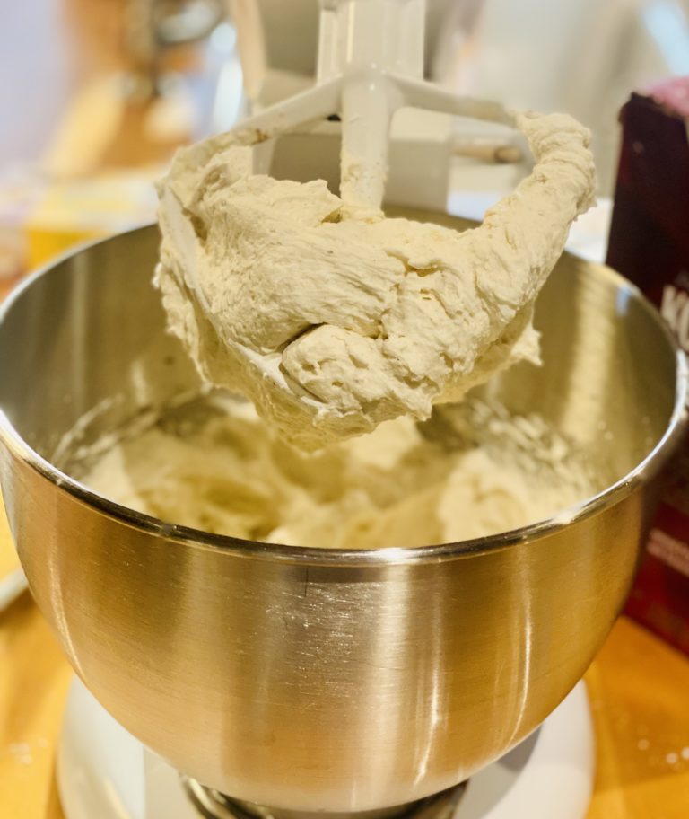 A mixing bowl and paddle attachment with cake batter on it. 