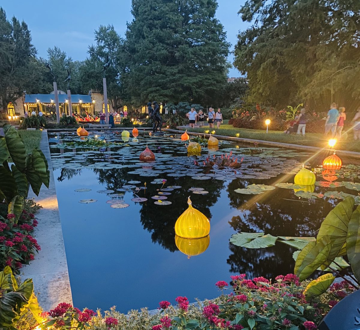 a reflecting pond filled with illuminated glass objects at twilight