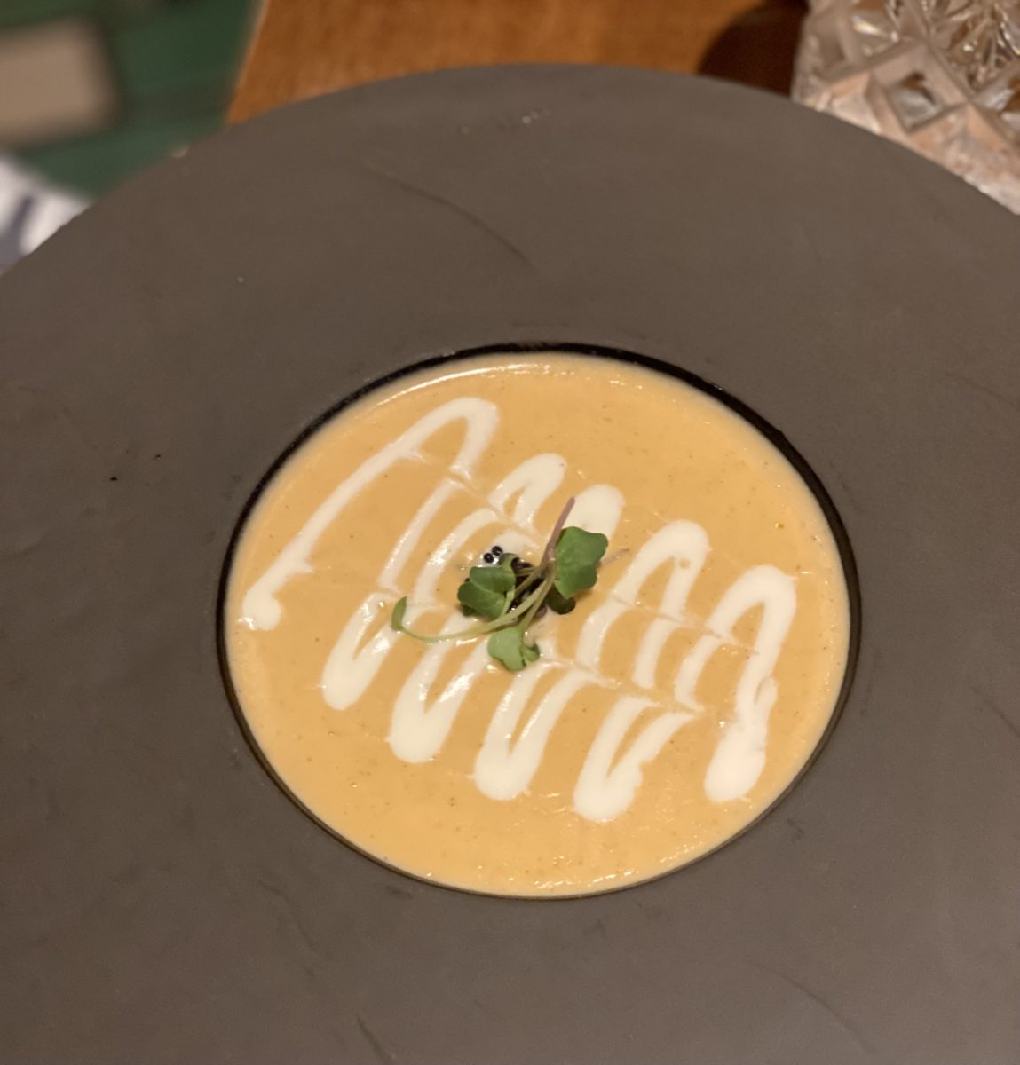 a matter black modern bowl filled with squash puree and a white drizzle of cream