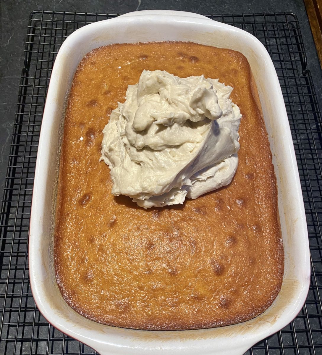 a cake in a 9 x 13 cake pan with a dollop of vanilla frosting on it 