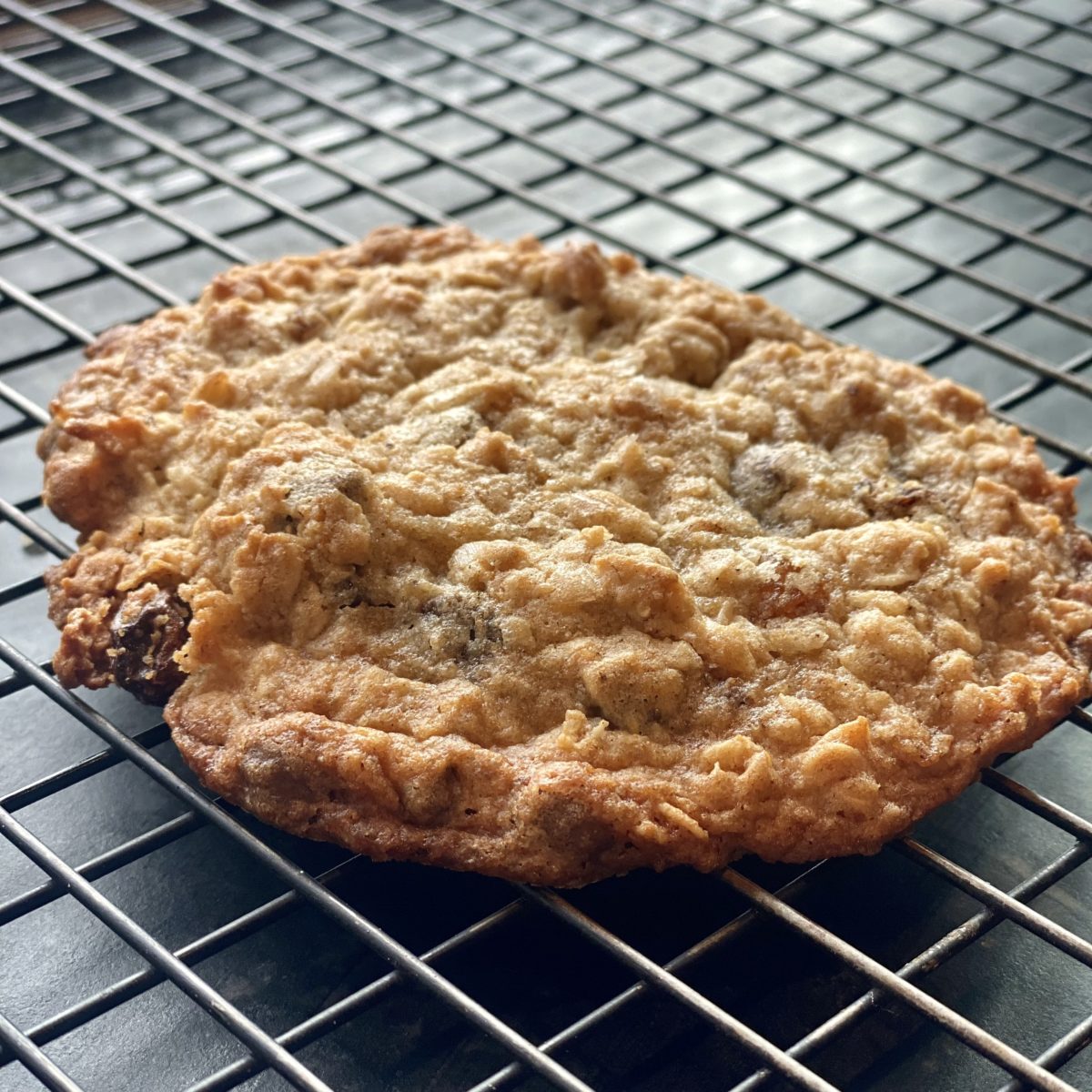 a large oatmeal cookie cooling on a black wire rack 