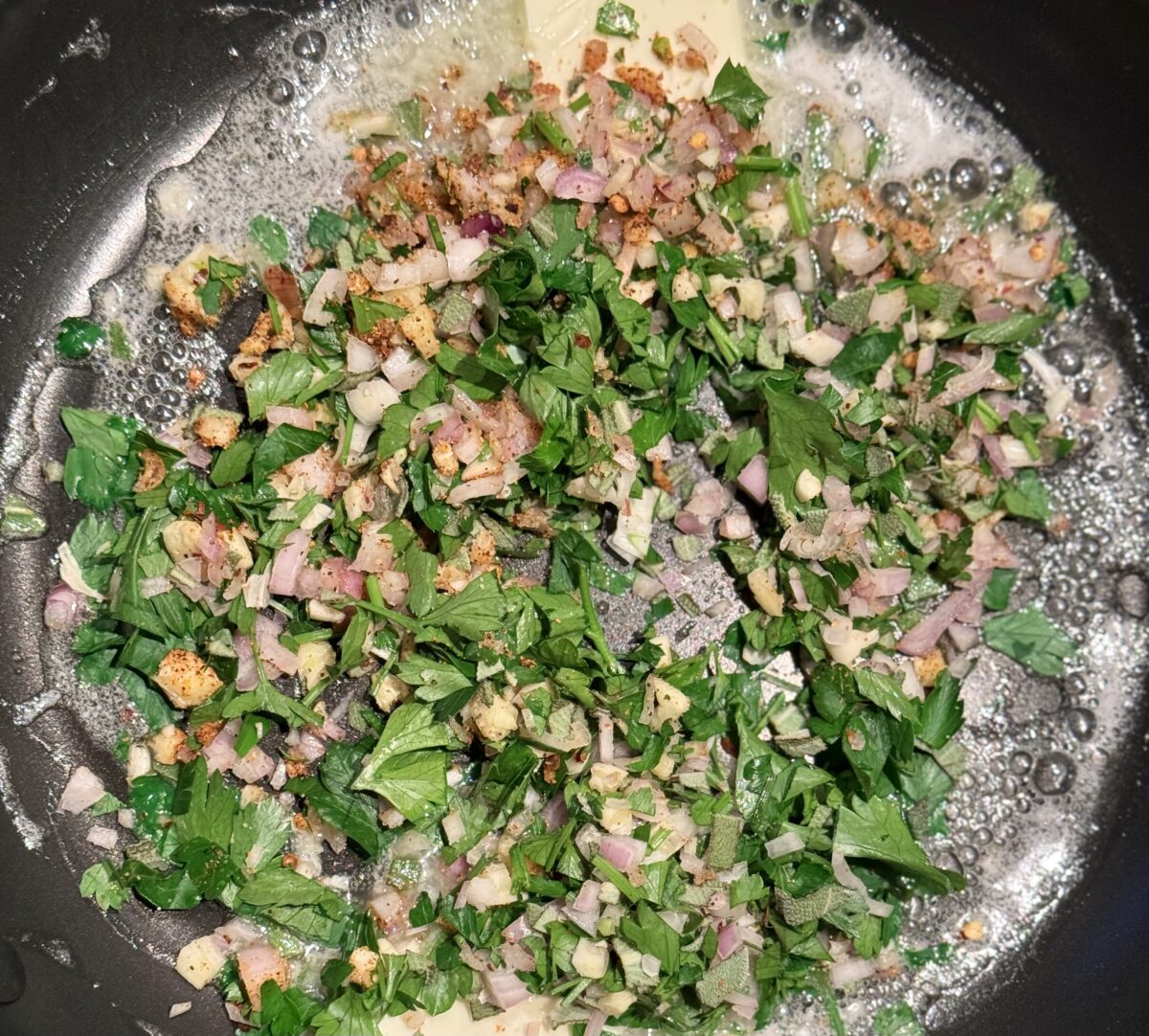 a pan of herb and garlic sautéing in butter 