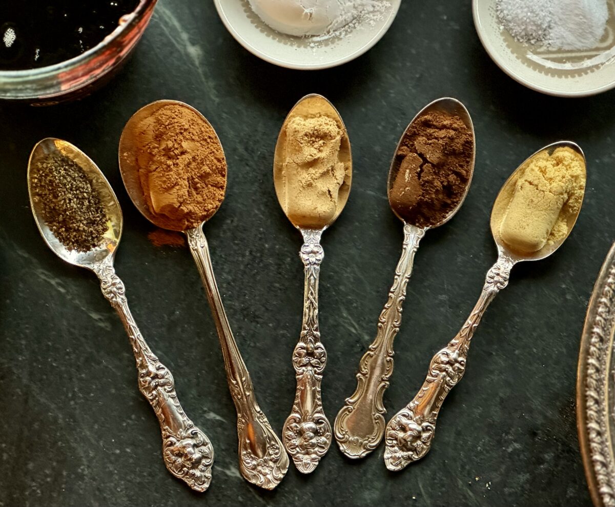 five silver teaspoons filled with spices