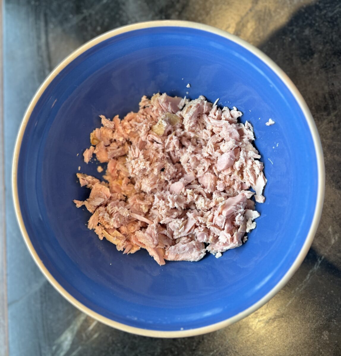a blue bowl filled with flaked canned tuna