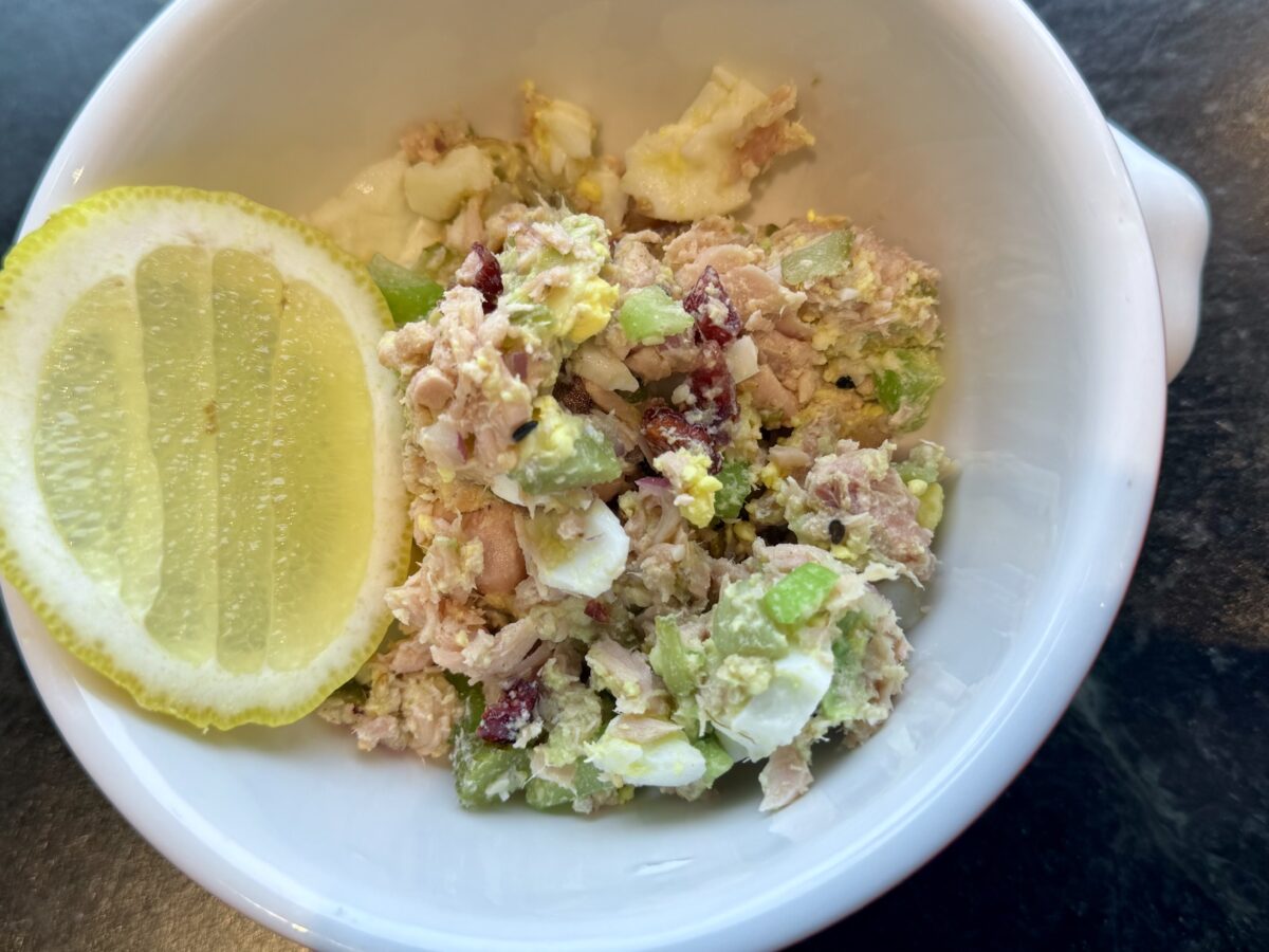 a white bowl with a lemon and tuna salad 