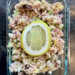 A rectangular glass dish with tuna salad topped with a lemon