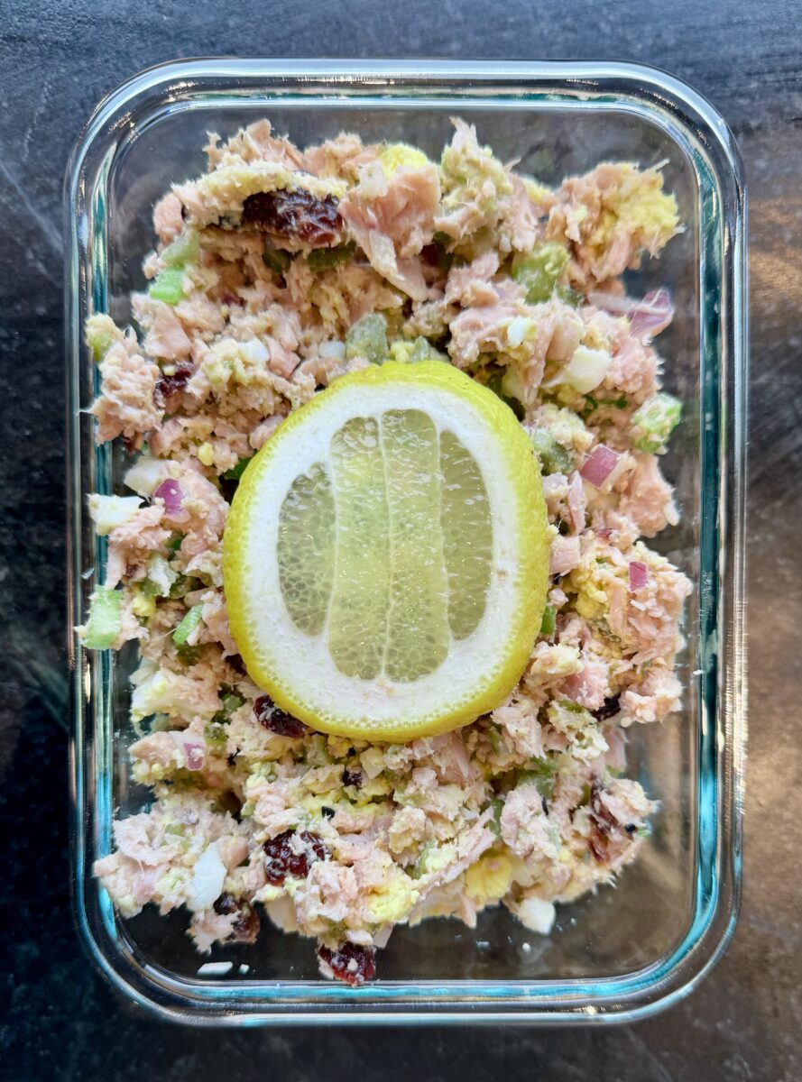 A rectangular glass dish with tuna salad topped with a lemon