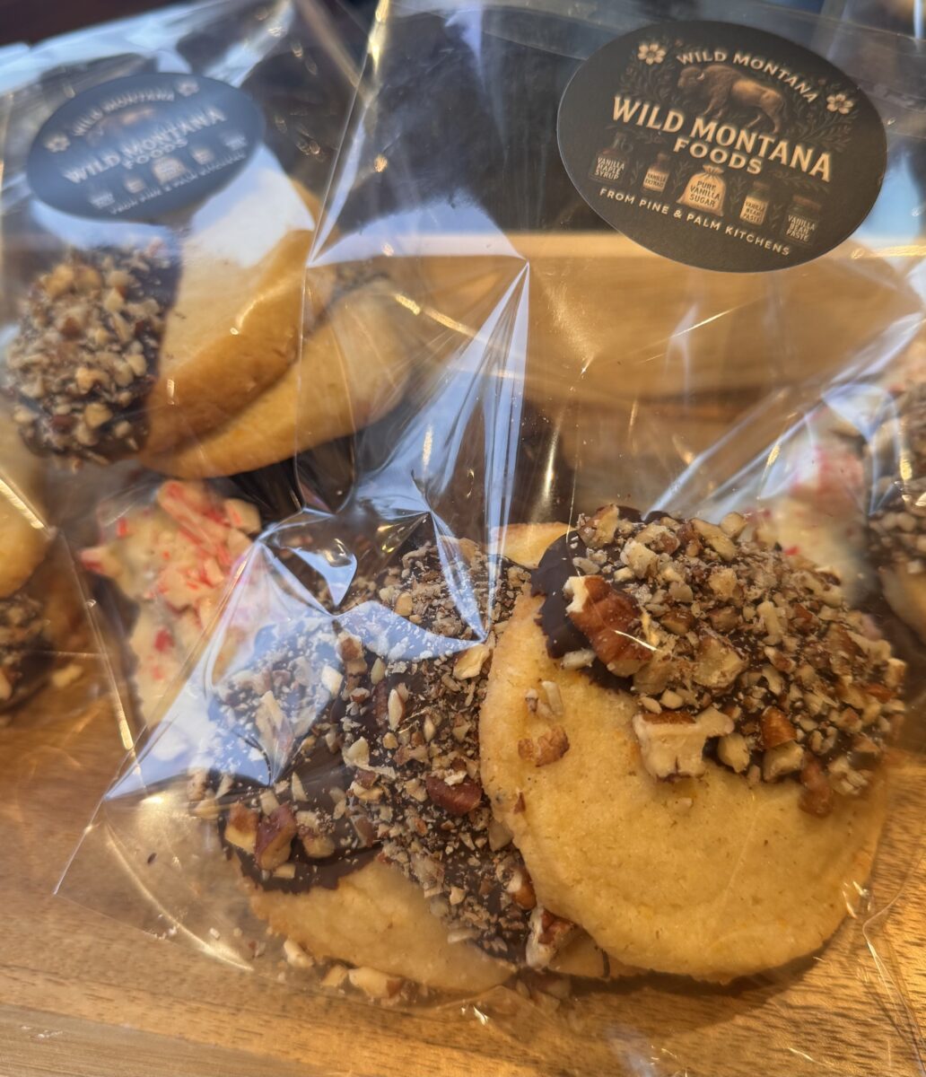 orange shortbread dipped in dark chocolate and sprinkled with finely chopped pecans inside a cellophane bag with a Wild Montana Foods sticker on the bag 