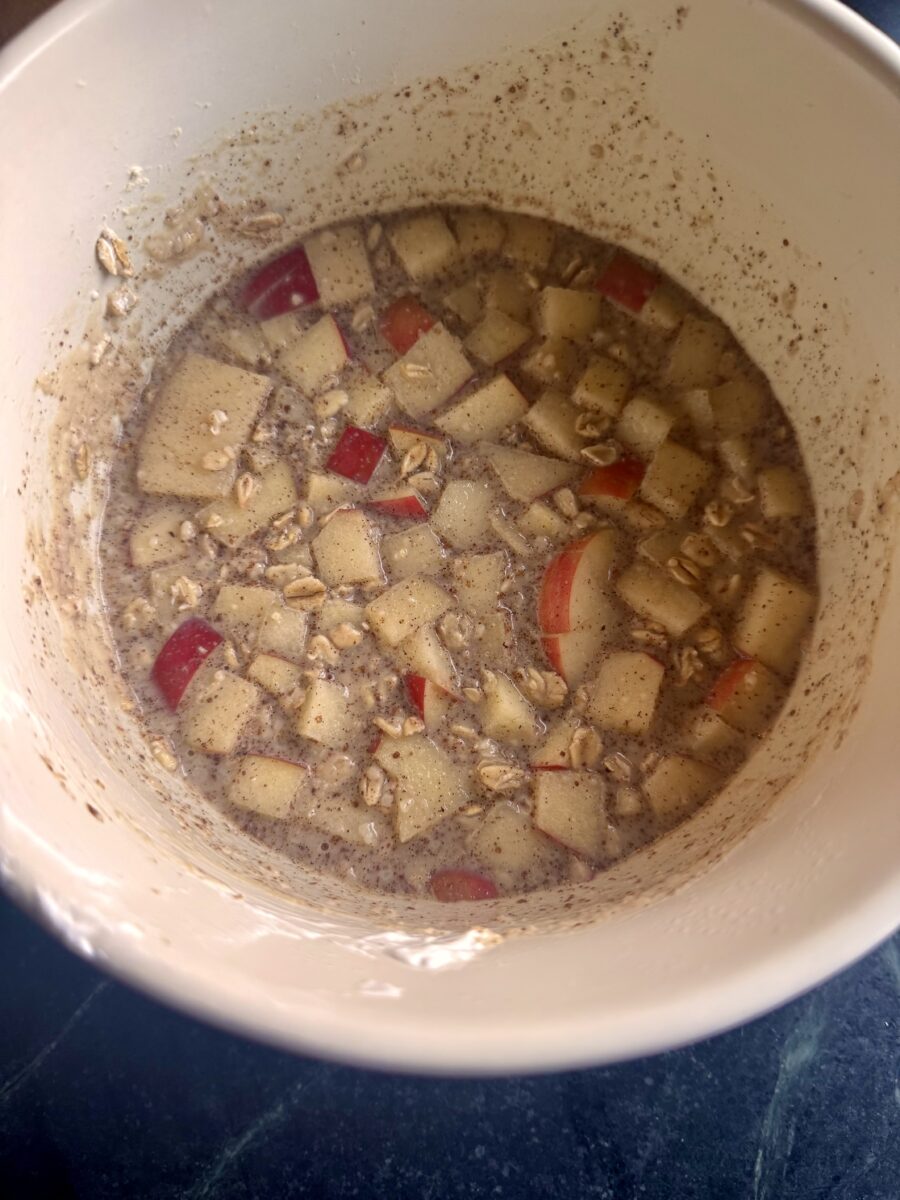 a ceramic bowl filled with chopped apples and overnight oats 
