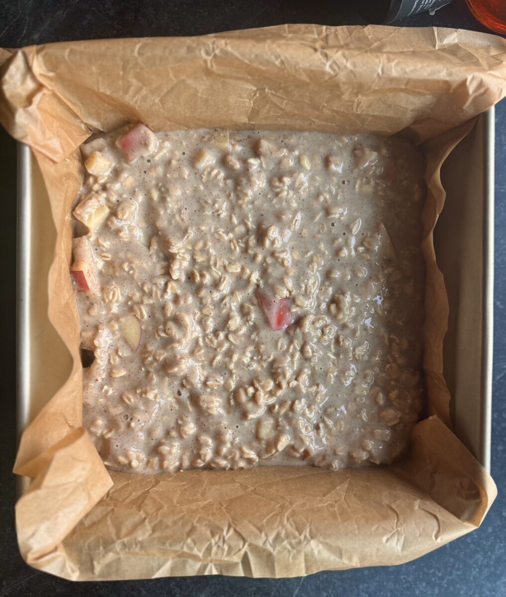 a square 8 x 8 inch baking pan lined with parchment paper g holding liquified overnight oats
