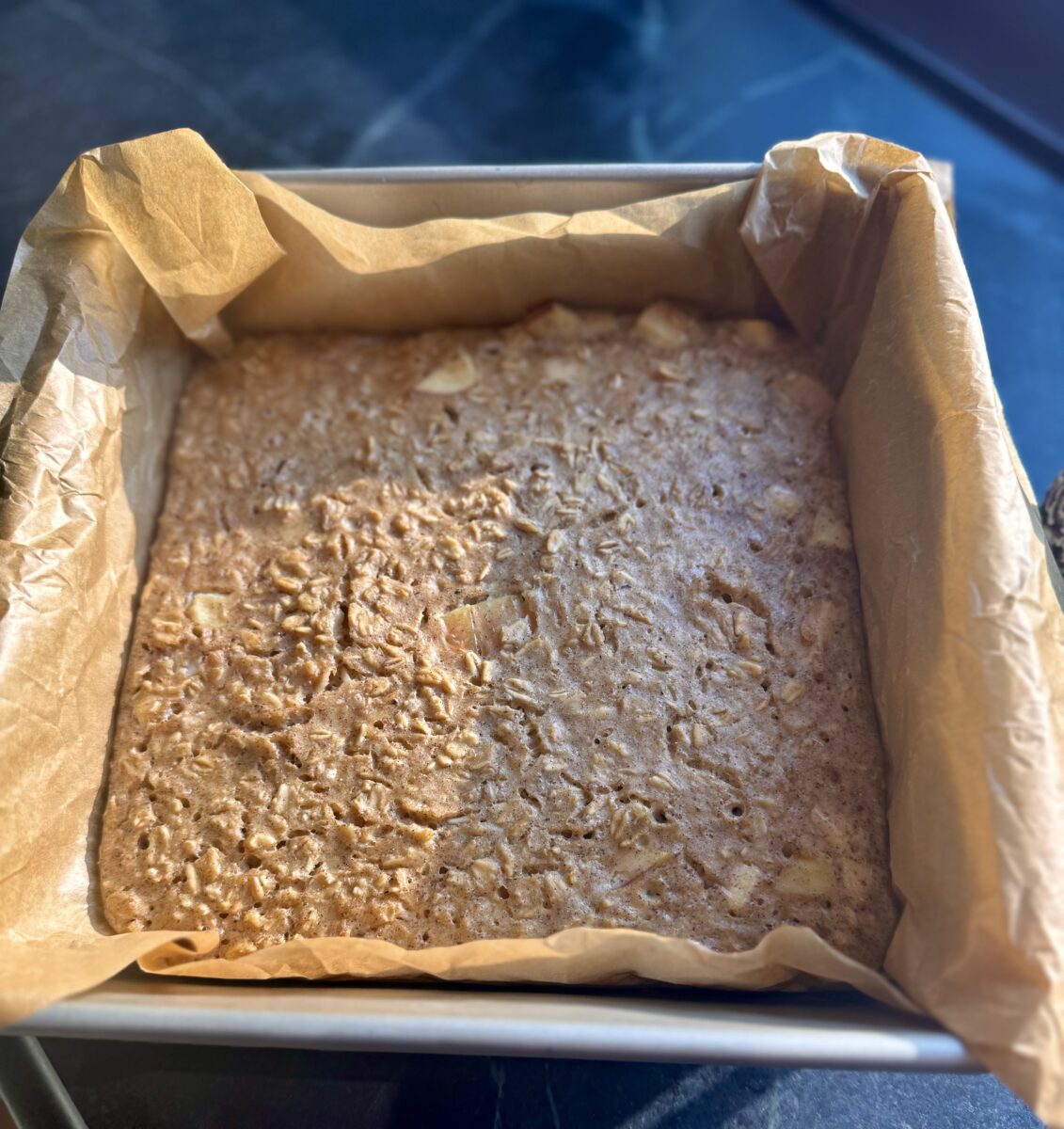 an 8 x 8 inch baking pan lined with parchment holding baked overnight oats 